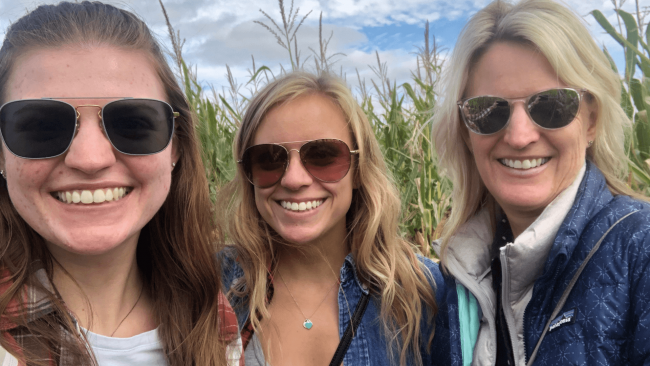 photo of Paige with her Mom and sister by a corn field all wearing sunglasses