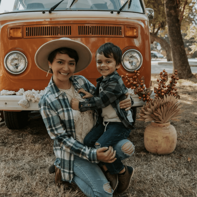 photo of Yesica with her son in front of an orange 1970's VW van