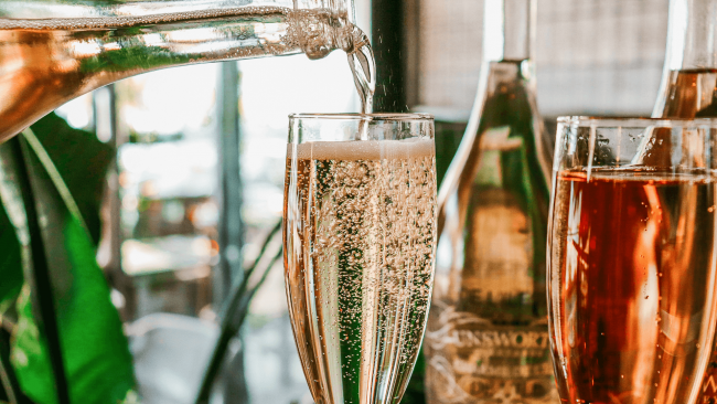 a glass of super fizzy rose wine being poured into the glass from the bottle