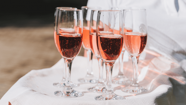 several glasses of pink rose champagne on a clothed tray