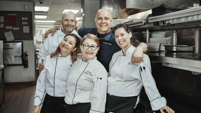 chef thomas with a few members of the Houston server team in the back of house all smiling and posing for a photo