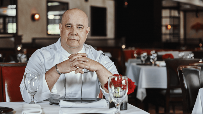 chef thomas seated in the dining room at a table with his hands folded