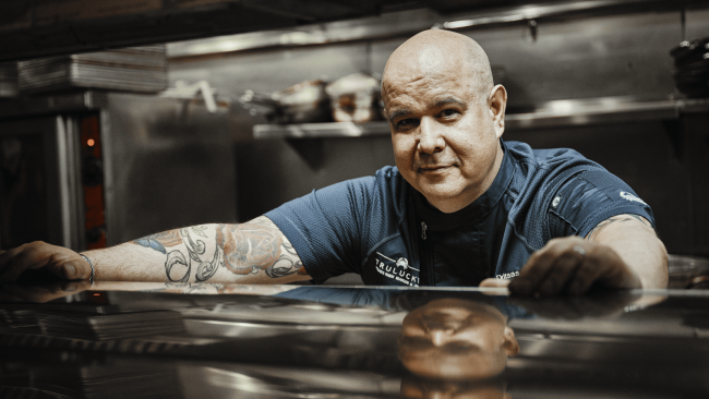 chef Thomas with his hands up on the kitchen line shelf, smiling