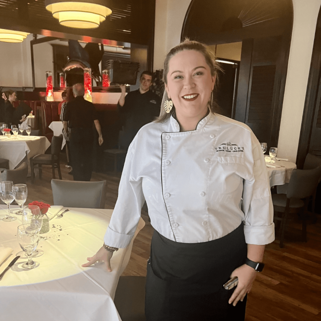 photo of server, Jen, in the Naples room main dining room with other teammates in the back ground during dinner service