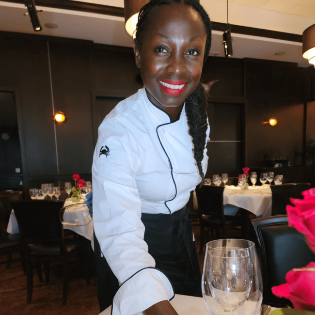 photo of Nyema a front of house server smiling and setting up a table in the dining room