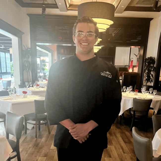 photo of Bryce who is a team assistant in the main dining room smiling and ready for service