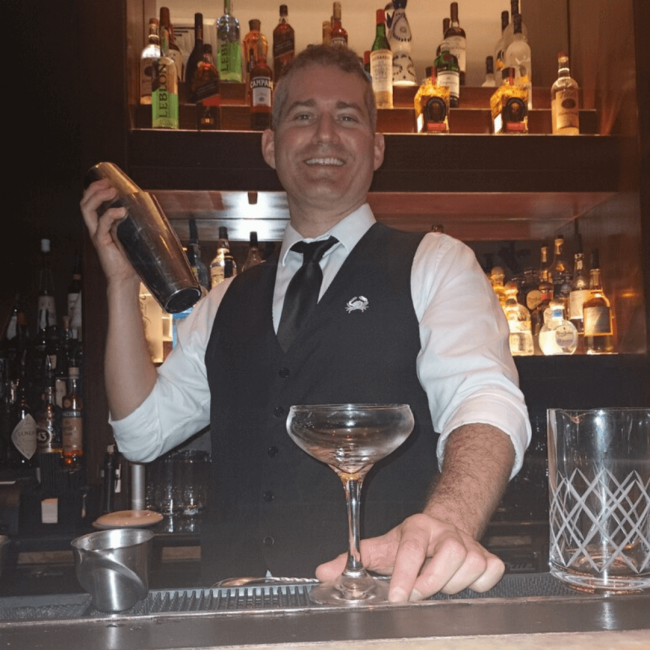 photo of bartender, David shaking an espresso cocktail in a shaker tin and getting ready to pour it