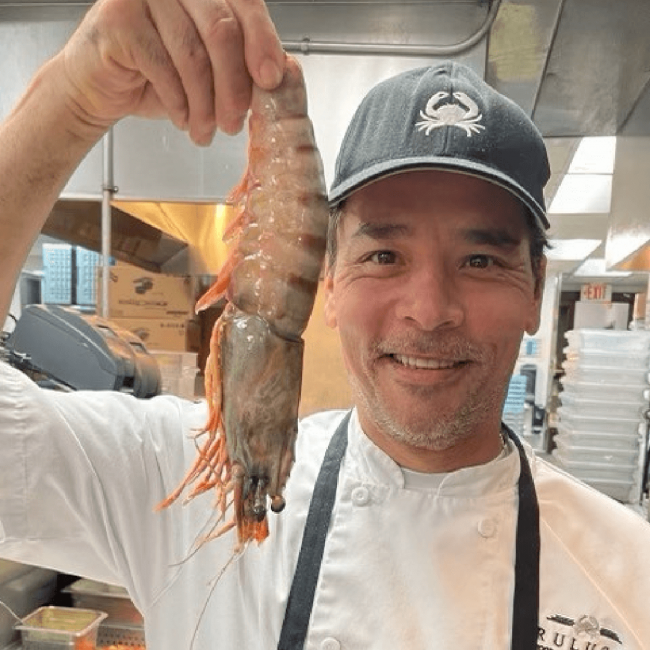 photo of our sous chef, Mario, holding a very large prawn shrimp