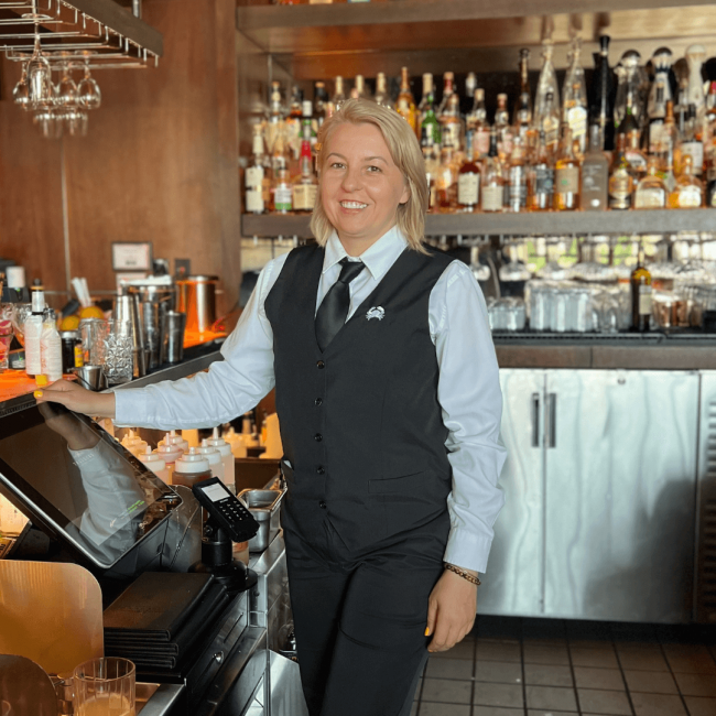 Truluck's Rosemont female bartender behind the bar smiling and prepping for happy hour