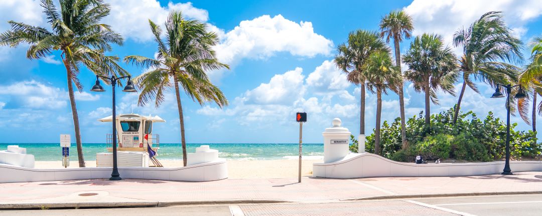 photo of the beach in Fort Lauderdale including palm trees, white sands and a lifeguard station