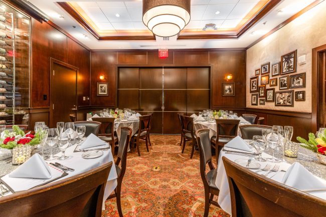 VIEW OF THE PRIVATE DINING ROOM IN MIAMI WITH THE POCKET DOORS PULLED CLOSED. FOUR ROUND TABLES AND CHAIRS SETUP