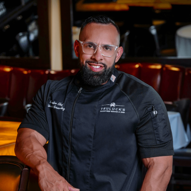 chef Estephan Fernandez in his black chef's coat in the lounge at the Naples location
