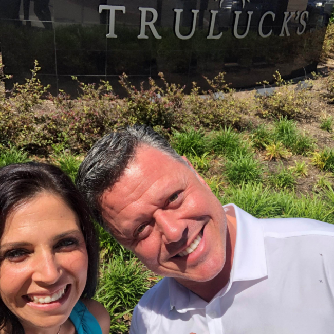 Tambra and Bo outside of the restaurant sign that says Truluck's