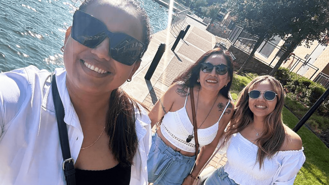 Paula and her daughters by the river front smiling