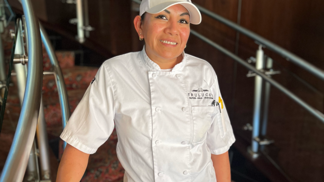 DFW pastry chef Paula Delgado in her chef coat and hat on the staircase in Dallas