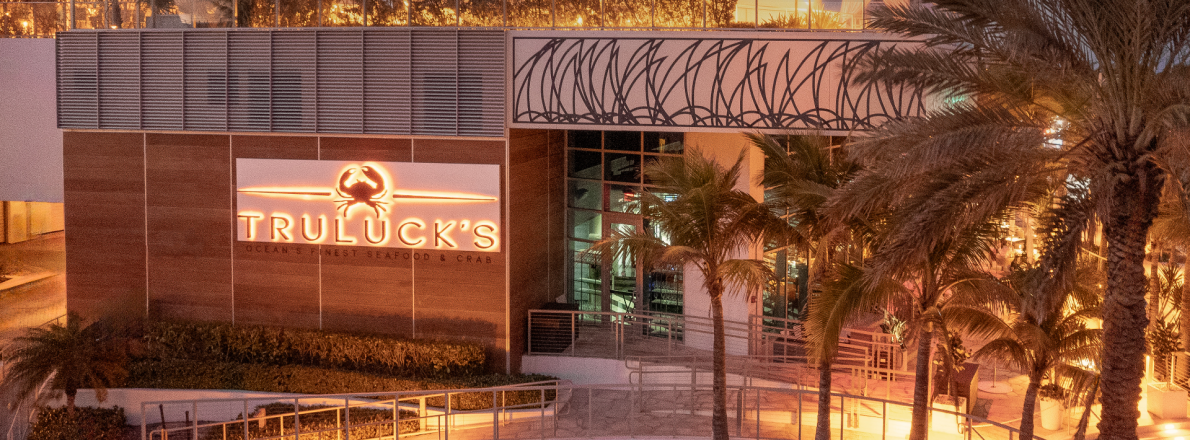 Truluck's Fort Lauderdale exterior entry with the lighted logo and palm trees in the forefront