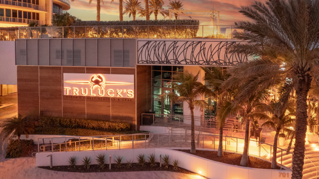 Truluck's Fort Lauderdale exterior entry with the lighted logo and palm trees in the forefront