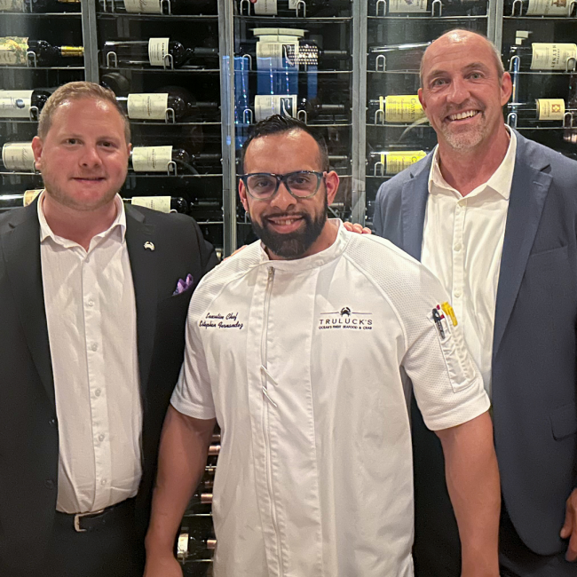 Chef Estephan with his leadership colleagues in front of the wine wall in Naples