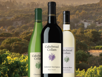 3 bottles of Cakebread cellars wine against the mountain range and vineyard