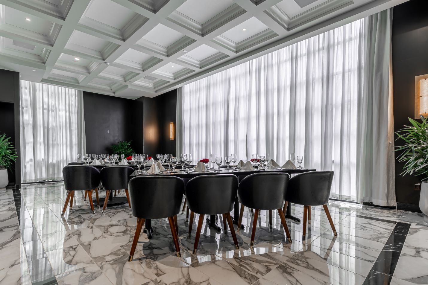 private Trident room at Truluck's Plano setup with navy leather chairs, black table tops, white linen napkins, glassware, red roses and marble tile floors with white decorative ceiling