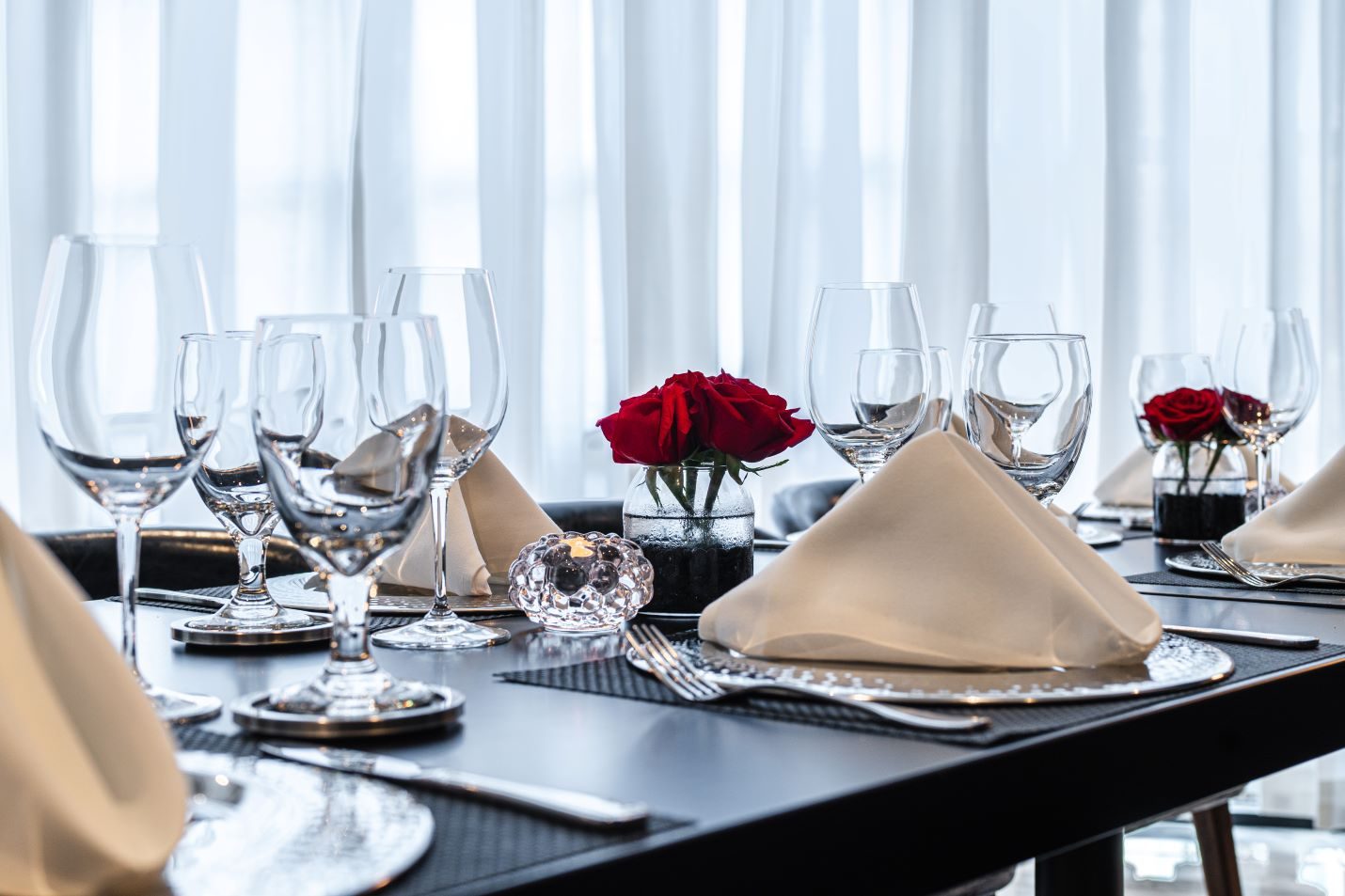 private Trident room at Truluck's Plano setup with navy leather chairs, black table tops, white linen napkins, glassware, red roses and glass candles