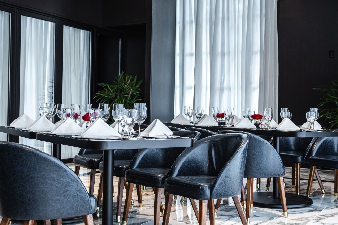 private Trident room at Truluck's Plano setup with navy leather chairs, black table tops, white linen napkins, glassware, red roses with draped doors and windows