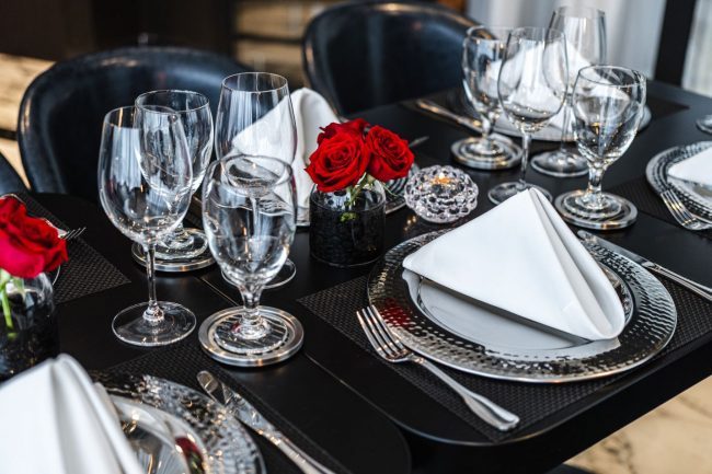 private Trident room at Truluck's Plano setup with navy leather chairs, black table tops, white linen napkins, glassware, red roses.