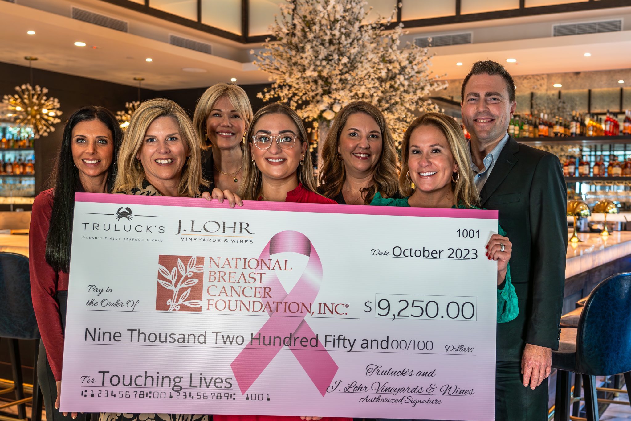 photo of the J. Lohr, NBCF and Truluck's team holding a big check made out to national breast cancer foundation for $9250 for breast cancer awareness month