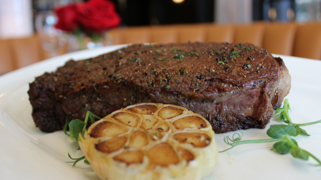 New York Strip steak seasoned with pepper, roasted garlic and greenery