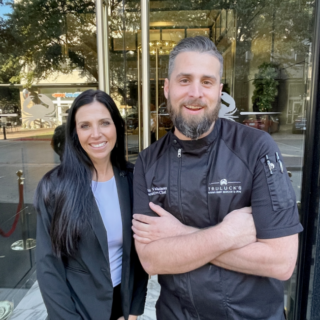 general manager Tambra Tatum with Chef Justin smiling outside of the front doors of Truluck's Plano