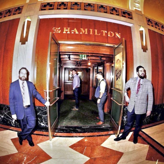 Keegan and Bond in suit and ties holding the doors open at The Hamilton restaurant
