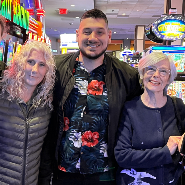 JT and his mom and grandma smiling in front of a few slot machines