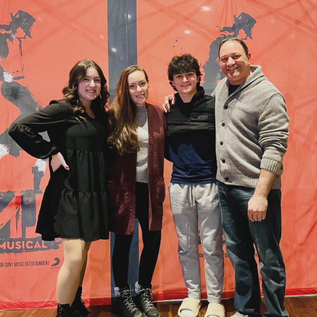 Yaniv with his wife and 2 children smiling and posted in front of a Michael Jackson backdrop