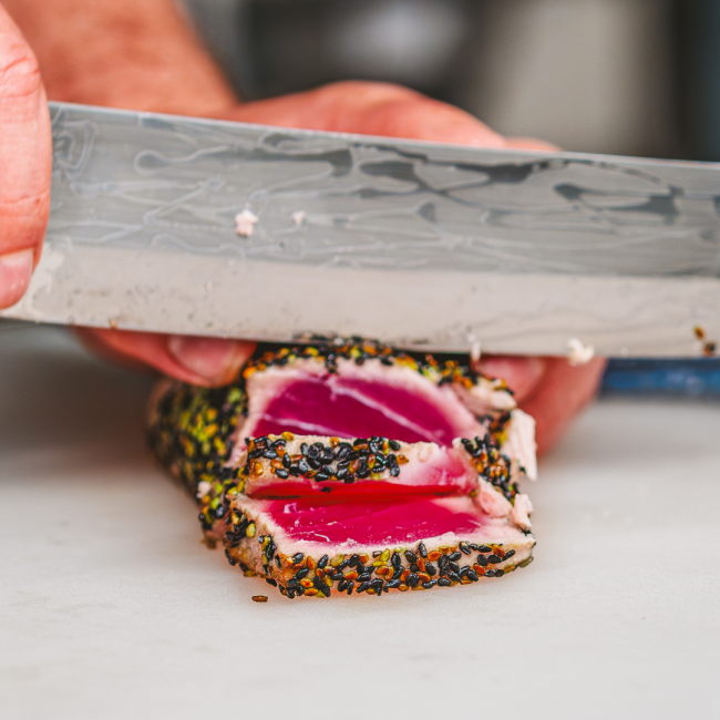 sesame tuna being sliced with a sharp knife by chef