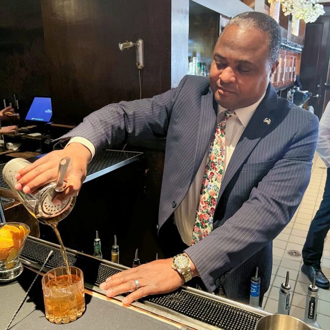 Southlake beverage manager Ken Alsop making a cocktail in the bar well and pouring it out of a shaker tin into a rocks glass filled with ice.