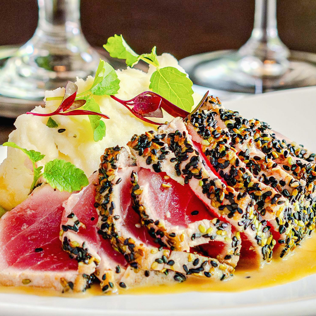 fresh ahi tuna crusted in black and white sesame seeds and seared rare with parmesan mashed potatoes, tamari wine butter sauce and dressed in microgreens