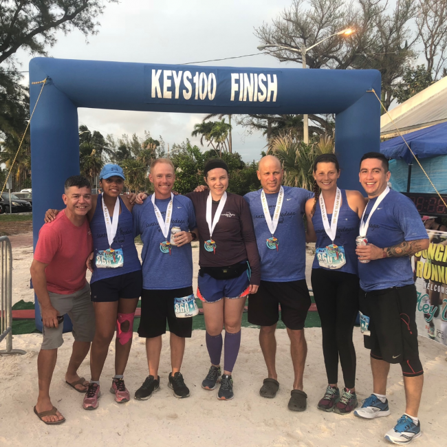 Fern and a group of friends after they finished a running race in front of the finish line.