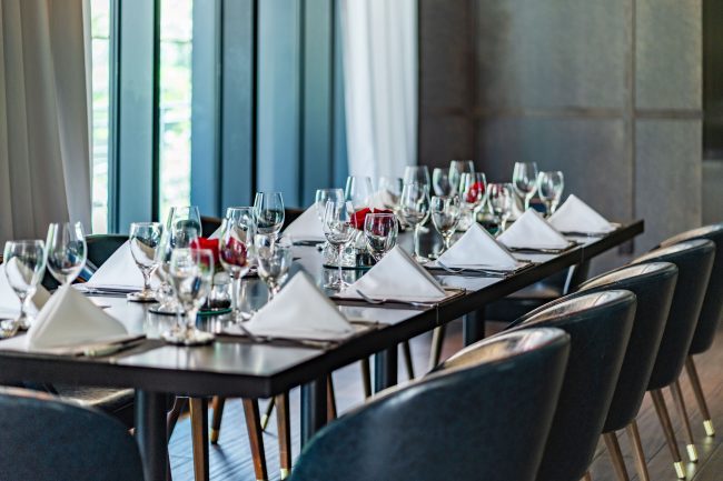 Truluck's Austin downtown mezzanine area with a close up photo of a boardroom style table set with china, glass, silver and white linen napkins.