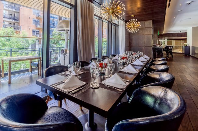 Truluck's Austin downtown mezzanine area with a large boardroom style table dressed in china, glass and silverware with gold sputnik style chandeliers