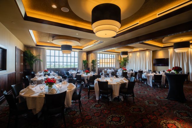 Truluck's Rosemont stone crab room view from the front left corner of the room. Tables dressed in white linen tablecloths with fresh flowers