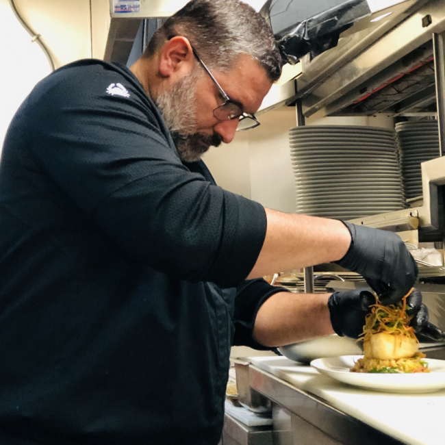 Chef Odel of Truluck's Miami garnishing a miso seabass in the back of house kitchen