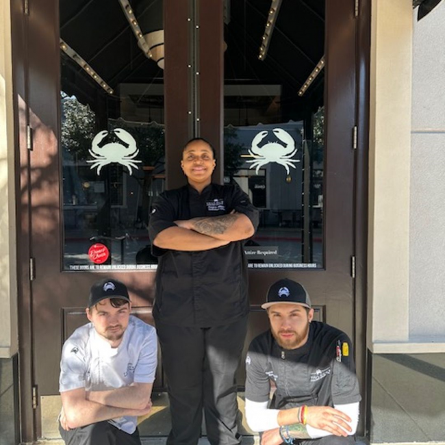 sous chef Kris Bell with Chef P of Southlake in front of the restaurant front door kneeling