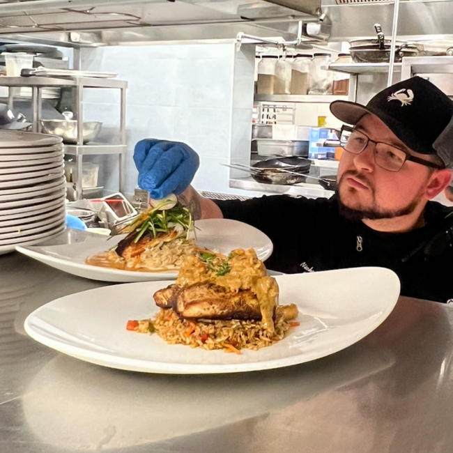 Chef Nick of Truluck's Austin garnishing entrees in the expo windo