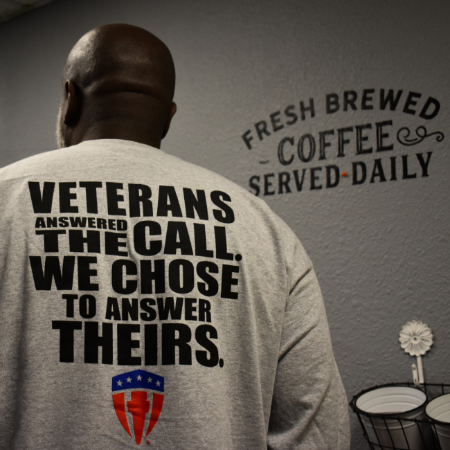 Veterans answered the call. We chose to answer theirs is written in all caps on the back of a gray sweatshirt. Fresh brewed coffee served daily is painted on the wall in the background.