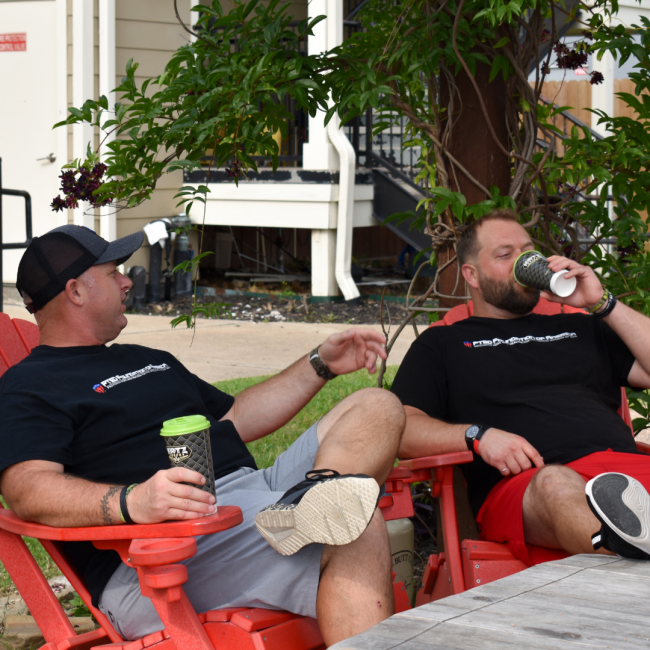 2 veterans sitting in red chairs drinking Katz coffee at the Camp Hope facility