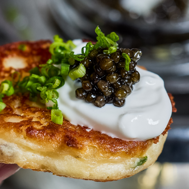 TRU Caviar atop a blini with creme fraiche and chopped chives