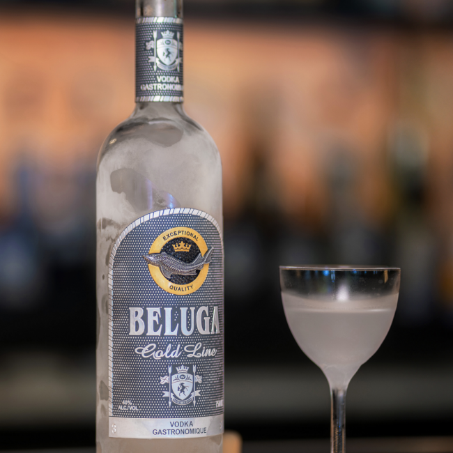 Beluga Gold Line Vodka Gastronomique bottle with frost on the bottle next to a Nick and Nora style glass filled with ice cold frosty vodka