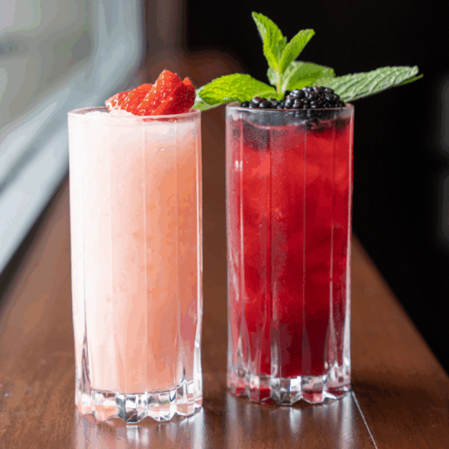 Blackberry Bramble and strawberry mocktails, two colorful non alcoholic drinks with fresh berry garnishes