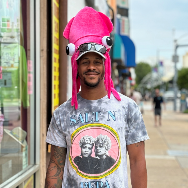 Chef Darryl with a funny squid hat on smiling on the sidewalk.