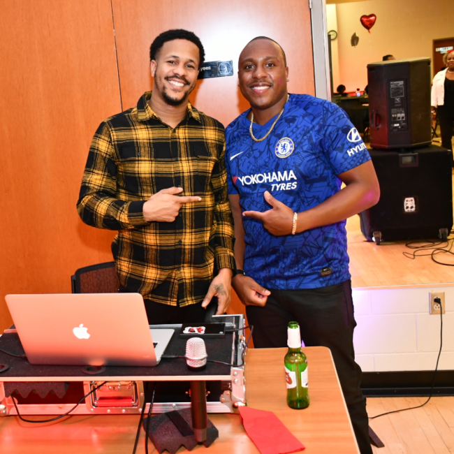 Chef Darryl and his buddy at a DJ event smiling and pointing at each other